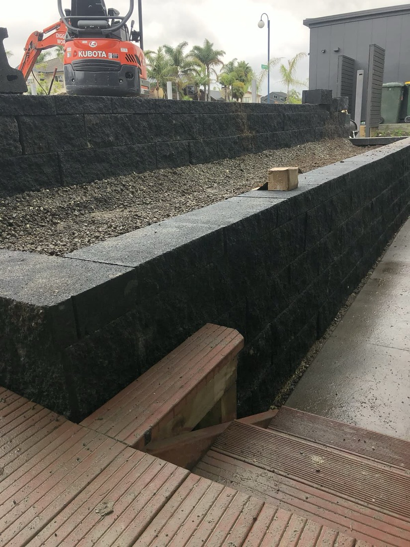 Black block retaining wall with excavator access above