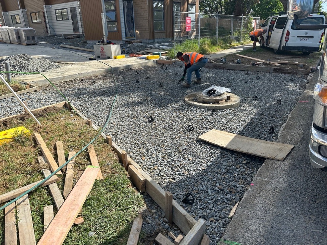 Concrete driveway base preparation with aggregate and reinforcing mesh before pouring