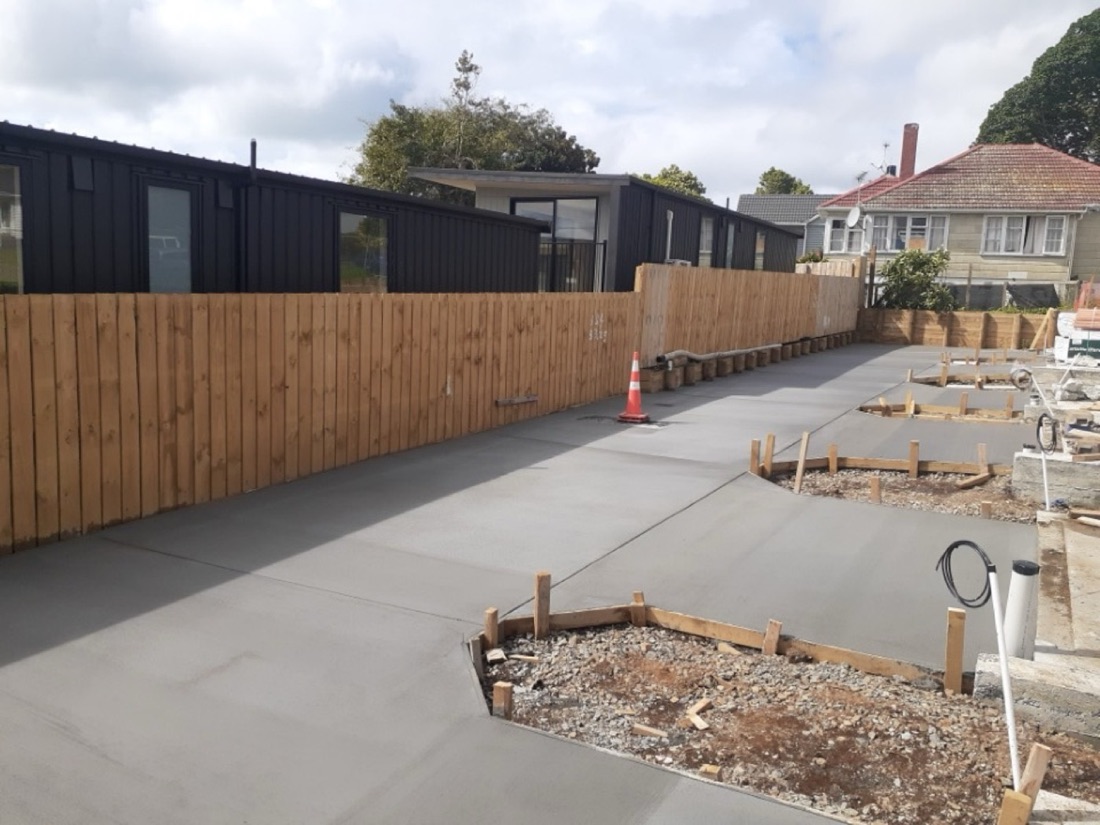 Concrete driveway beside timber fencing and garden areas