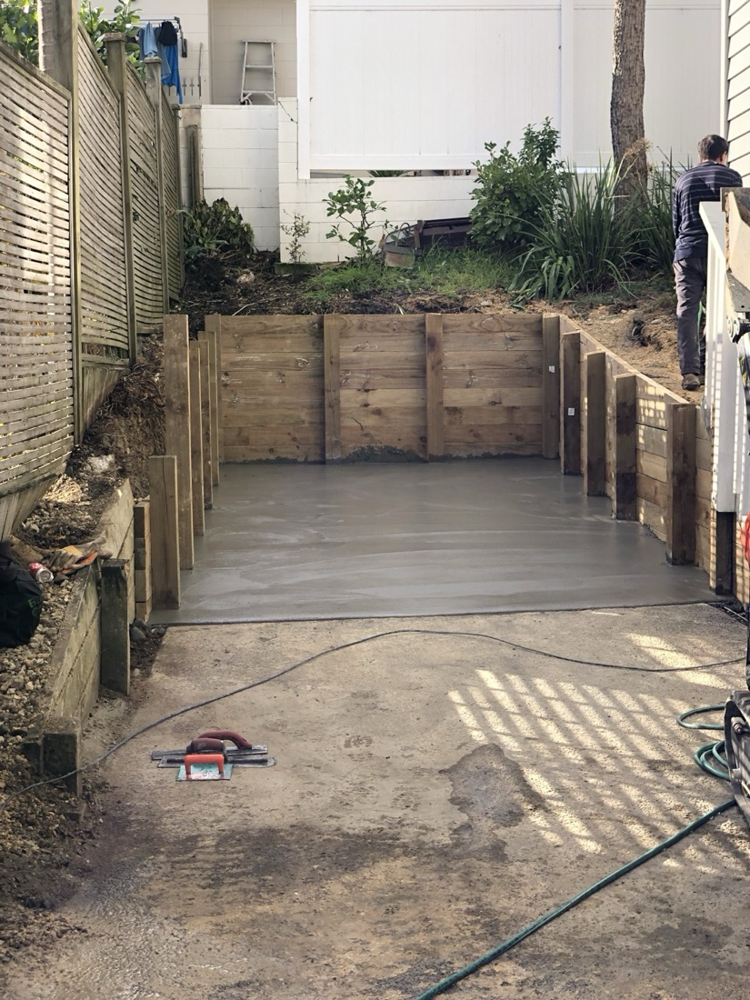 Concrete pad with timber retaining wall support in a residential outdoor area