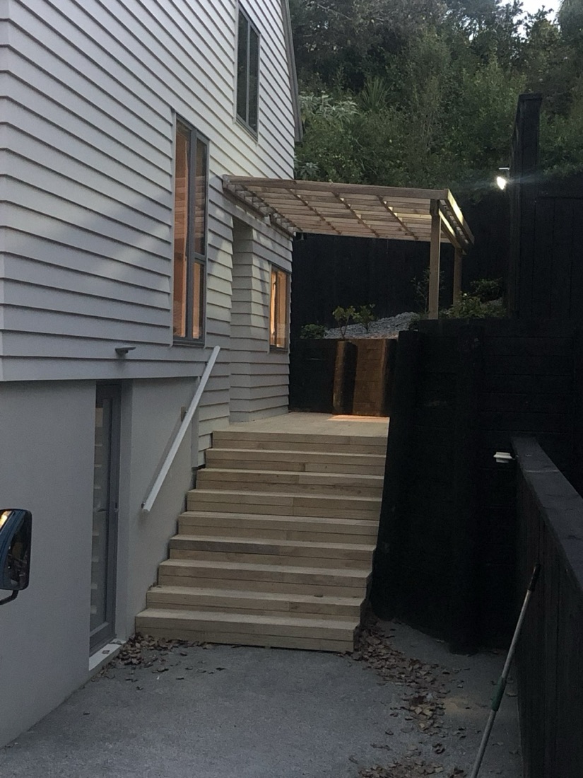 Timber deck stairs and covered entry beside a house
