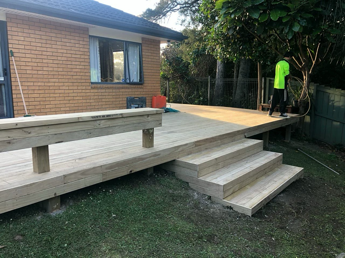 Timber deck with broad steps beside a brick home